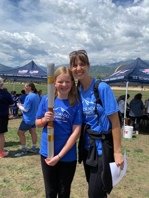 A mom and her child pose with a retired Olympic torch