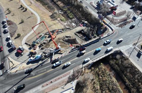 An aerial view shows ongoing construction on the 8th Street bridge over Fountain Creek. Just downstream, a smaller temporary bridge allows crews and equipment to safely cross the creek.