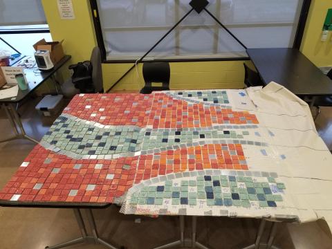 a mural made of small, hand-panted square tiles is being put together on a table.