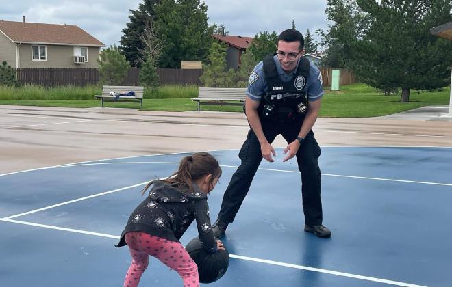 police officer playing basketball with a little girl
