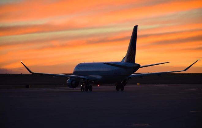 airplane on the runway with orange sunset sky