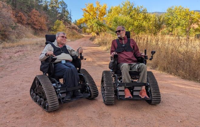 Two residents use PRCS track chairs on a dirt trail.