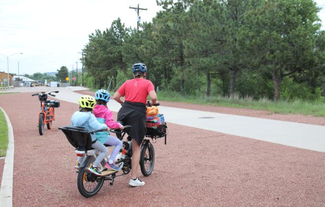 A mom bikes on an urban trail with her children.