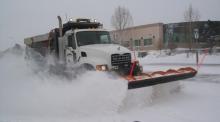photo of a snowplow plowing the street