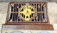 Stormwater drain with a gold USA basketball grate cover 